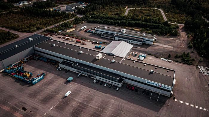 Ilmakuva Terästuotteen tuotantotiloista Raahen Kiiluntiellä: pitkä tuotantohalli ja varastokenttä metsän keskellä.